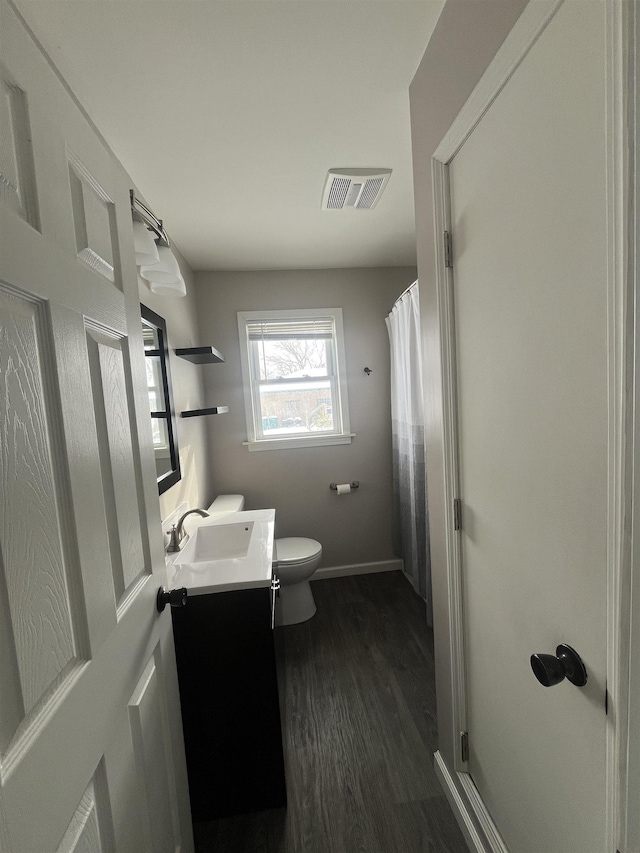 full bathroom with visible vents, a shower with shower curtain, toilet, wood finished floors, and vanity