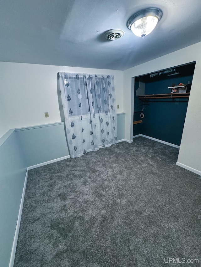 unfurnished bedroom with dark carpet, visible vents, and baseboards