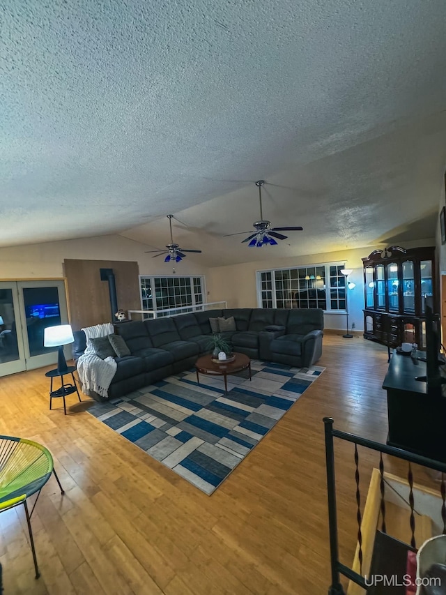 living room with a ceiling fan, vaulted ceiling, a textured ceiling, and wood finished floors