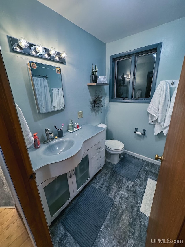 bathroom featuring toilet, wood finished floors, vanity, and baseboards