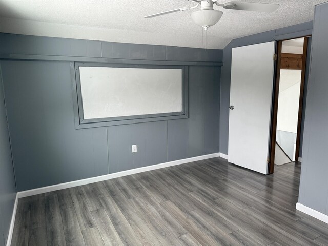 empty room with dark wood-style floors, ceiling fan, a textured ceiling, and baseboards