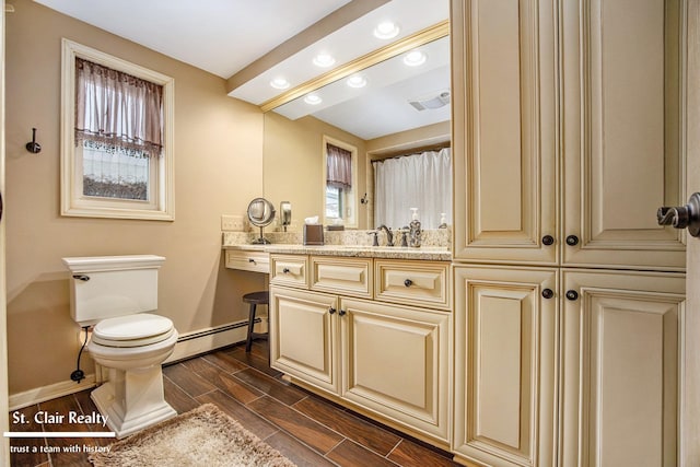 bathroom featuring wood finish floors, visible vents, baseboard heating, vanity, and baseboards