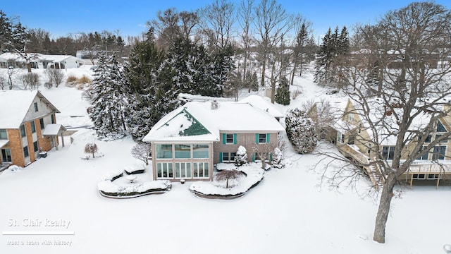 snow covered rear of property featuring a garage