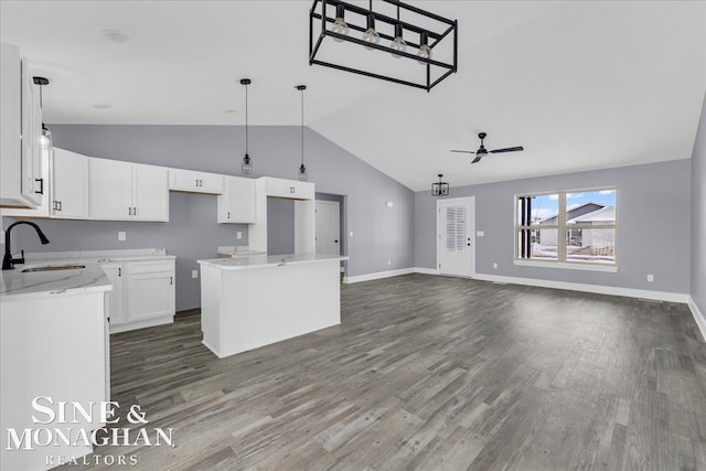 kitchen featuring ceiling fan, a sink, white cabinetry, a center island, and dark wood-style floors