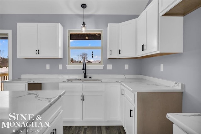 kitchen featuring hanging light fixtures, light stone countertops, plenty of natural light, and a sink