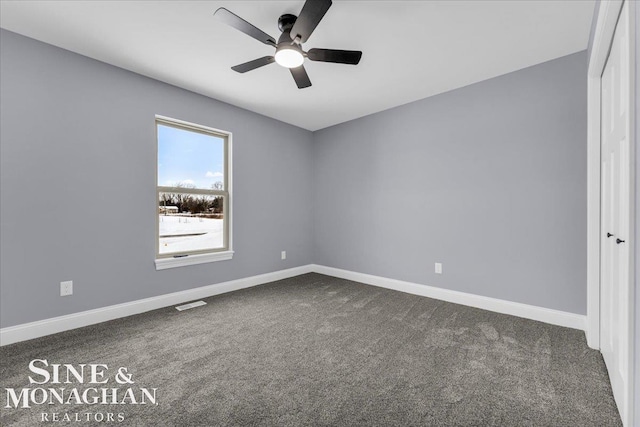 empty room with ceiling fan, dark carpet, visible vents, and baseboards