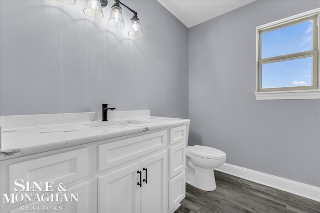 bathroom featuring baseboards, vanity, toilet, and wood finished floors