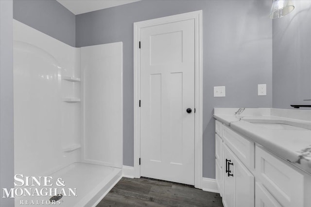 bathroom with baseboards, walk in shower, wood finished floors, and vanity