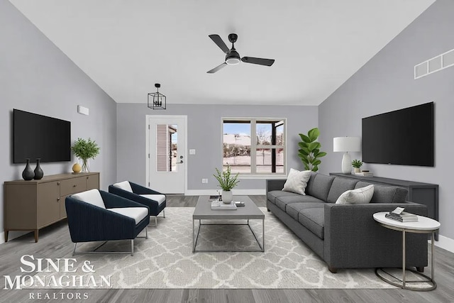 living room featuring lofted ceiling, visible vents, light wood-style flooring, and baseboards