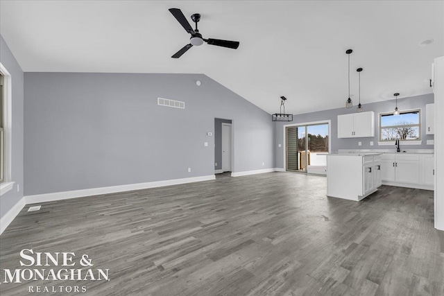 unfurnished living room featuring visible vents, a ceiling fan, vaulted ceiling, wood finished floors, and baseboards