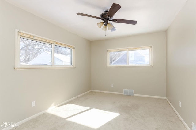 spare room with light carpet, a wealth of natural light, visible vents, and baseboards