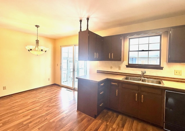 kitchen with a wealth of natural light, backsplash, a sink, and decorative light fixtures