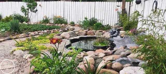 view of yard with fence and a garden pond