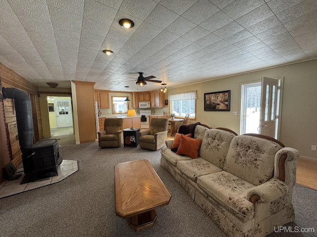 carpeted living room featuring a wood stove and baseboards