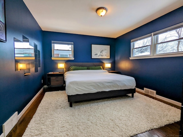 bedroom with visible vents, dark wood finished floors, and baseboards