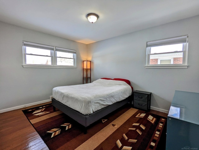 bedroom featuring dark wood-style flooring, multiple windows, and baseboards