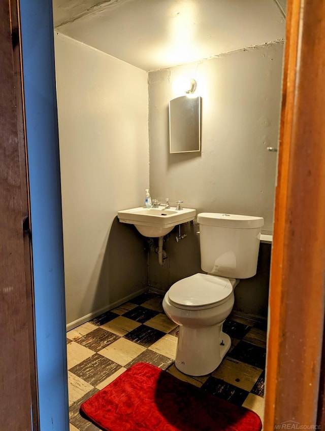 half bathroom featuring baseboards, a sink, toilet, and tile patterned floors