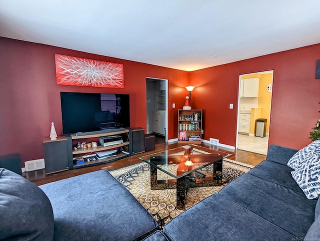 living room with baseboards, visible vents, and wood finished floors