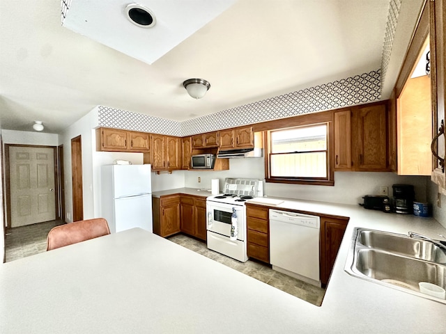 kitchen featuring light countertops, white appliances, brown cabinetry, and under cabinet range hood