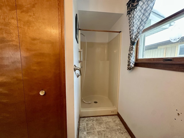 full bathroom with a stall shower and baseboards