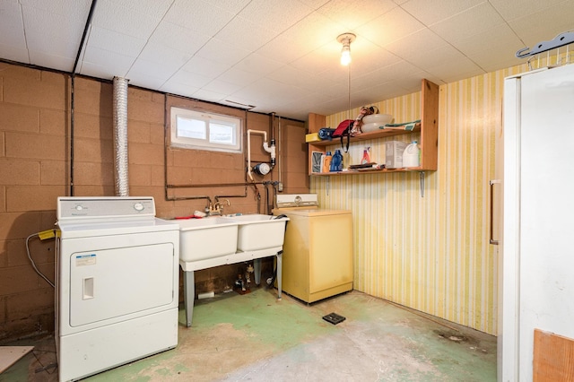 clothes washing area featuring laundry area, separate washer and dryer, a sink, and concrete block wall