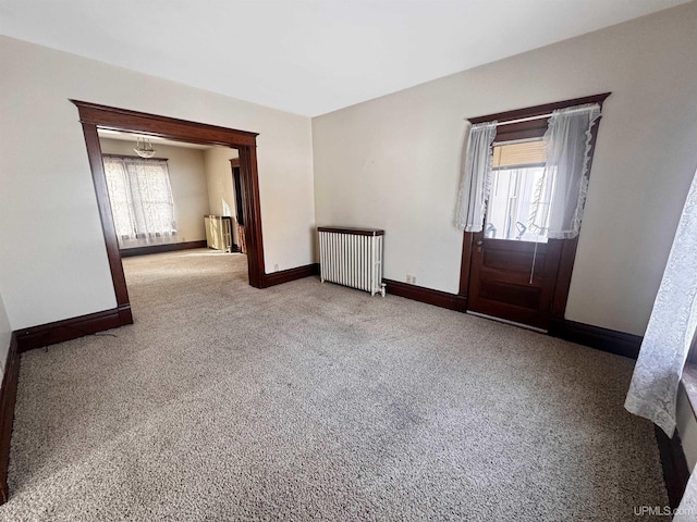 spare room with radiator, baseboards, and carpet flooring