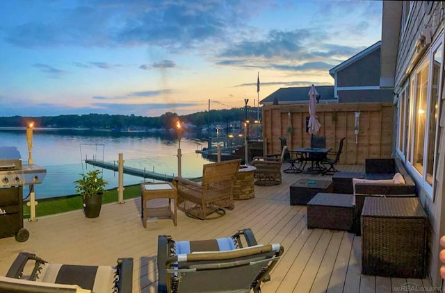 exterior space featuring area for grilling, a deck with water view, and an outdoor living space with a fire pit