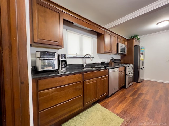 kitchen with stainless steel appliances, dark wood-type flooring, a sink, ornamental molding, and brown cabinetry