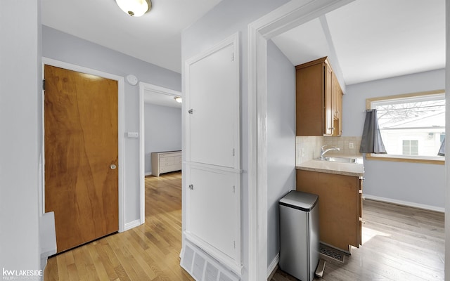 bathroom featuring wood finished floors, a sink, visible vents, and tasteful backsplash