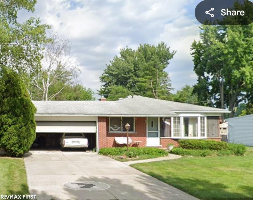 ranch-style home with a garage, concrete driveway, brick siding, and a front lawn