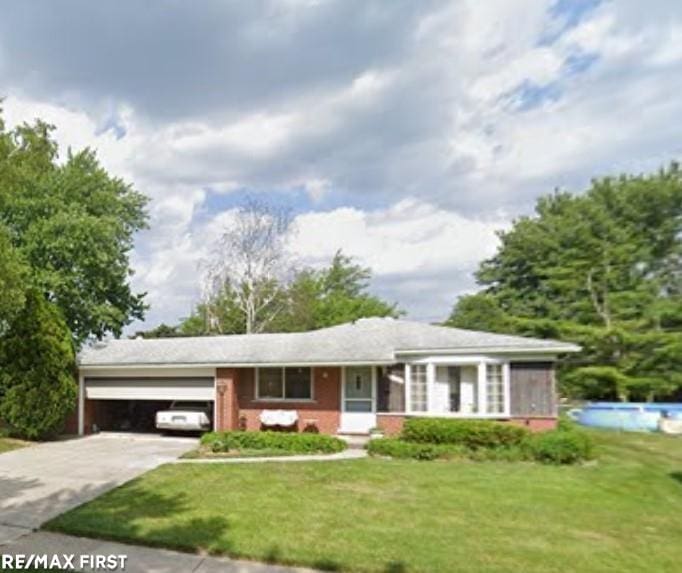 ranch-style home featuring a garage, a front yard, concrete driveway, and brick siding