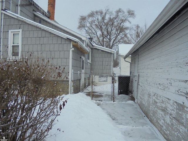 3606 Cadieux Rd, Detroit, MI 48224 - view of snowy exterior with a chimney, fence, and a gate