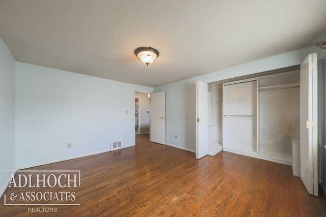 unfurnished bedroom featuring dark wood-style floors, a closet, visible vents, and baseboards