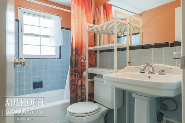 bathroom featuring shower / bath combo, toilet, and tile walls