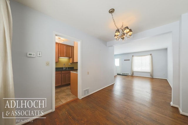 interior space with a chandelier, a sink, dark wood finished floors, and visible vents