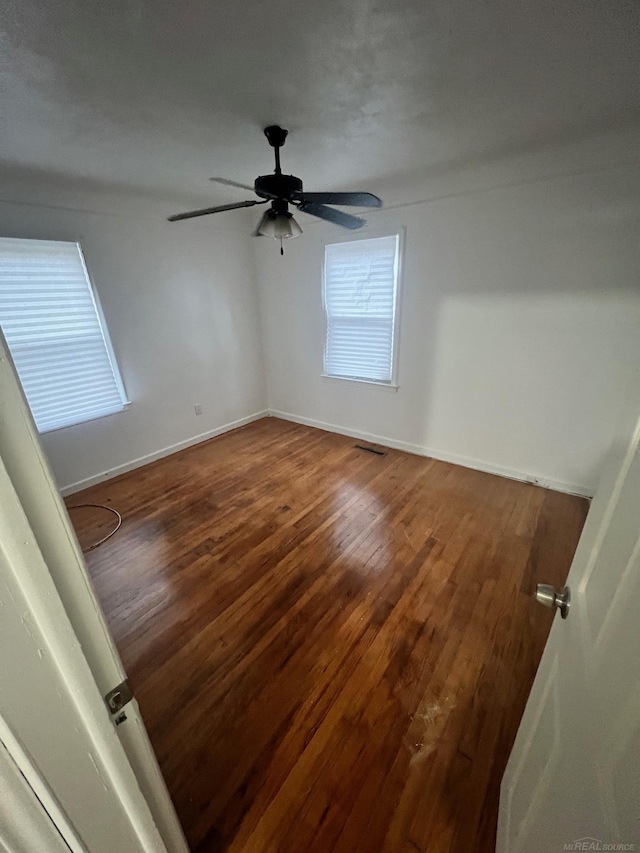 spare room with a ceiling fan, dark wood-style flooring, and baseboards