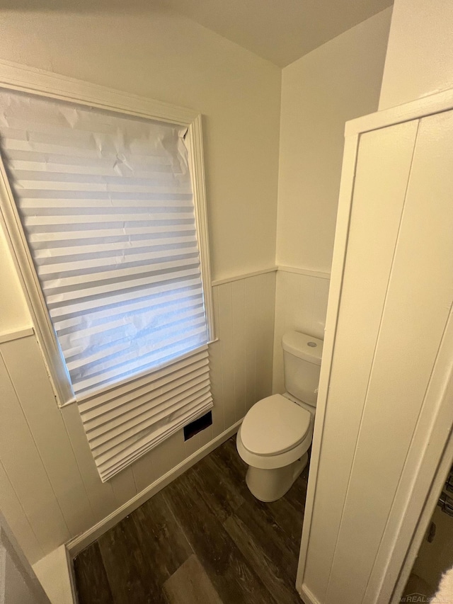 bathroom with toilet, wood finished floors, and wainscoting