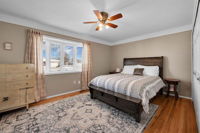 bedroom featuring dark wood-style flooring, a ceiling fan, and baseboards