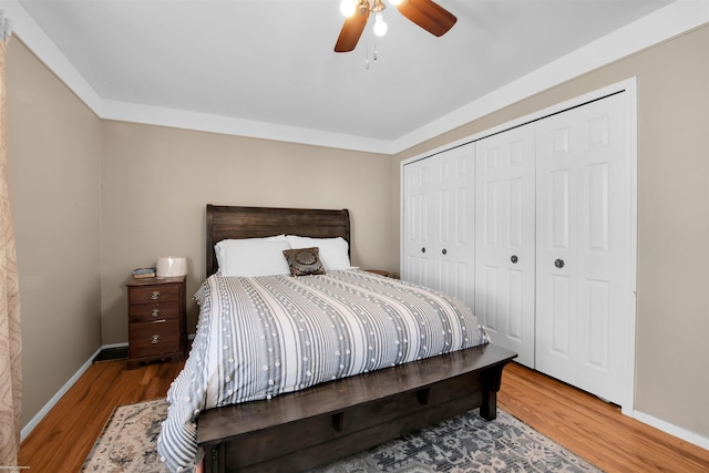 bedroom featuring a closet, wood finished floors, a ceiling fan, and baseboards