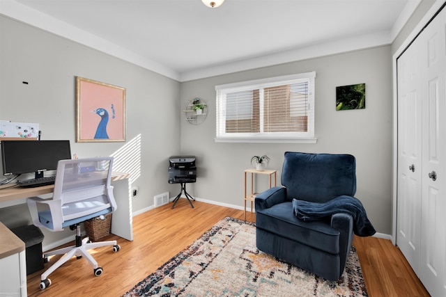 office space featuring baseboards, visible vents, and wood finished floors