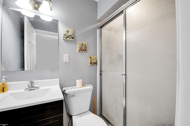 bathroom featuring toilet, a shower with door, and vanity