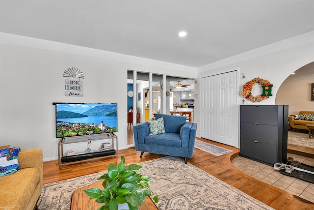 living area featuring a ceiling fan, arched walkways, light wood finished floors, and recessed lighting