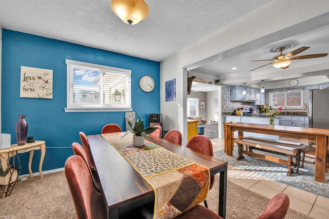 dining space featuring ceiling fan, a textured ceiling, baseboards, and light tile patterned floors