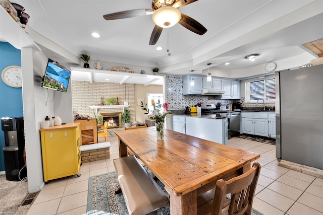 dining space with a brick fireplace, light tile patterned flooring, and a healthy amount of sunlight