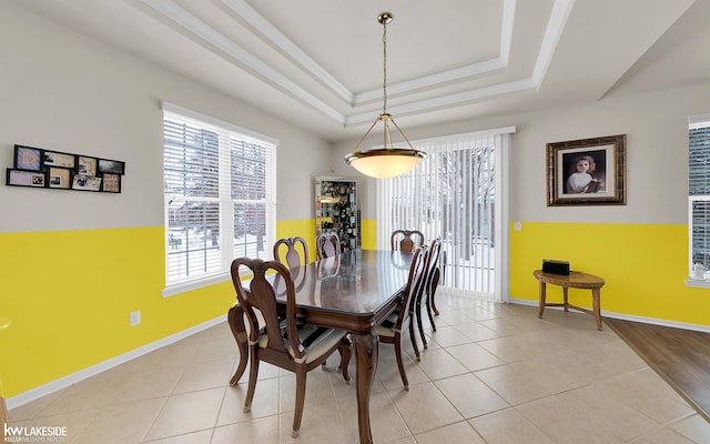 dining room with light tile patterned floors, baseboards, and a tray ceiling