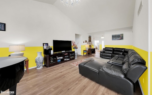 living area with baseboards, visible vents, light wood-type flooring, high vaulted ceiling, and a notable chandelier