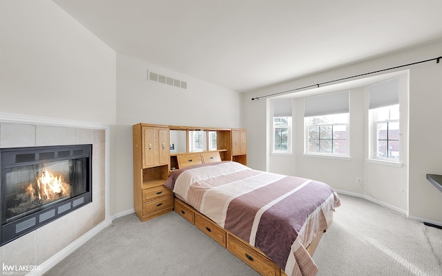 bedroom featuring light carpet, baseboards, a fireplace, and visible vents