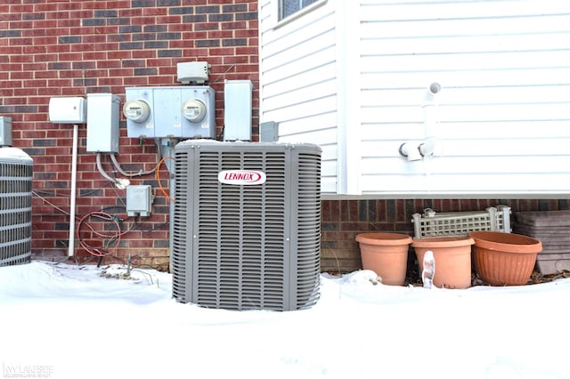 details featuring electric meter, central AC unit, and brick siding