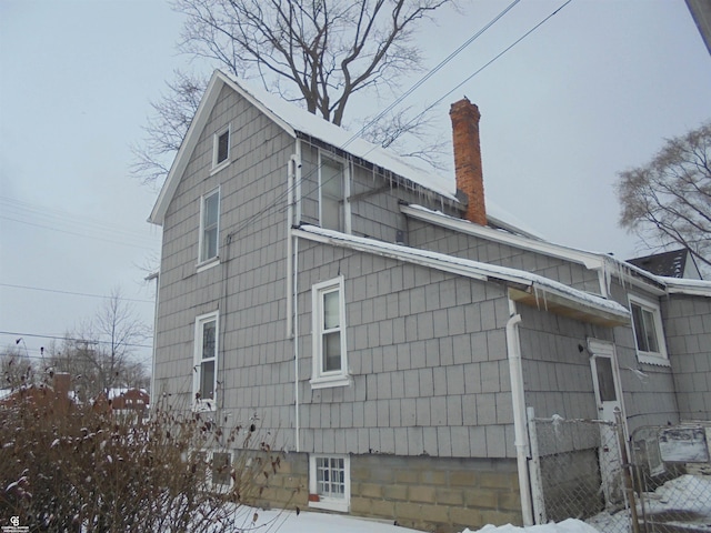 view of snowy exterior with a chimney