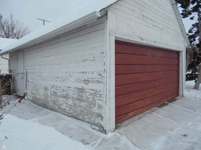 snow covered garage with fence